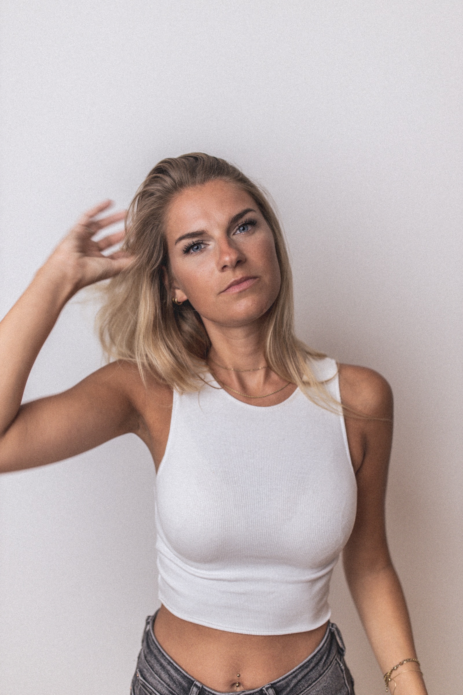 Portrait einer Frau im weißen Top vor hellem Hintergrund